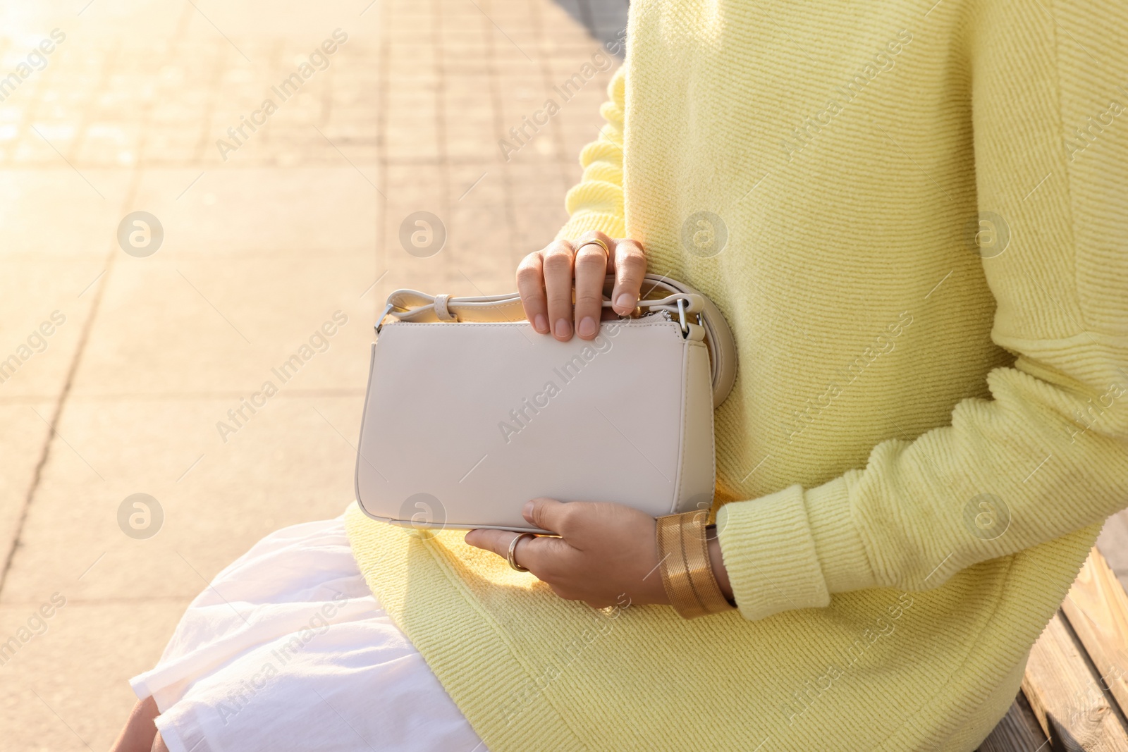 Photo of Fashionable woman with stylish bag on bench outdoors, closeup