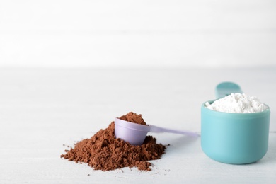 Photo of Scoops of different protein powders on white table, space for text