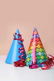 Photo of Colorful party hats, streamers and blower on white table. Birthday celebration