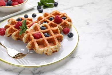 Photo of Delicious Belgian waffles with fresh berries and mint on white marble table, closeup