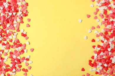 Photo of Bright heart shaped sprinkles on yellow background, flat lay. Space for text