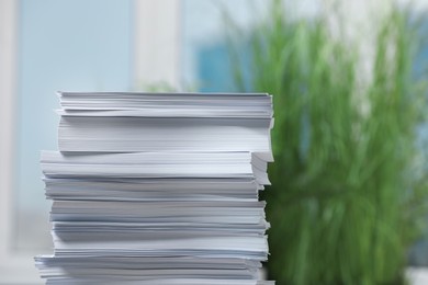 Photo of Stack of paper sheets against blurred background. Space for text