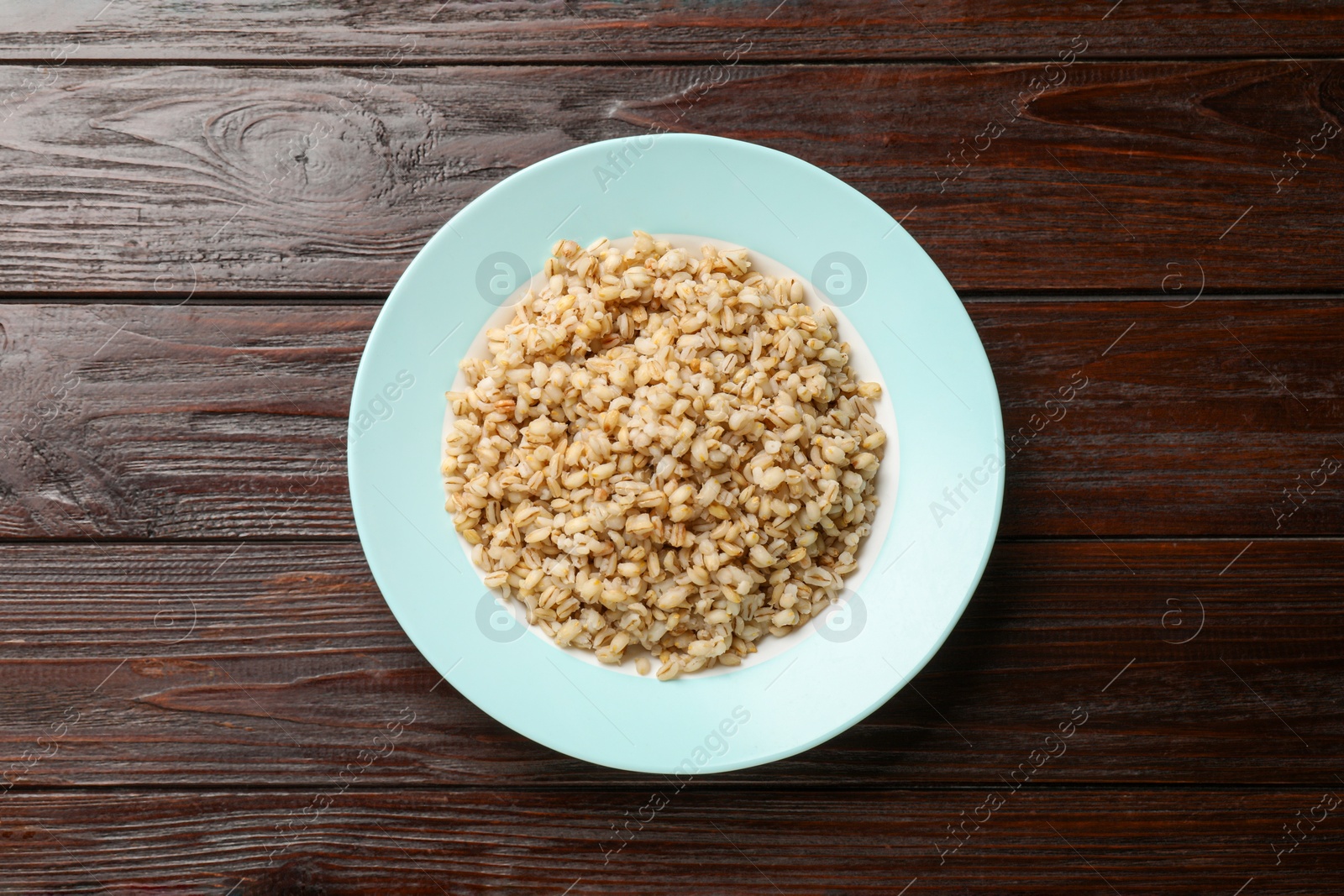 Photo of Delicious pearl barley on wooden table, top view