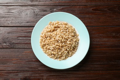 Photo of Delicious pearl barley on wooden table, top view