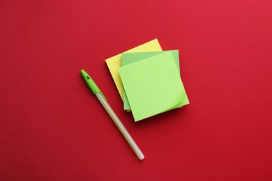 Paper notes and pen on red background, flat lay
