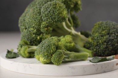 Photo of Tray with fresh raw broccoli on white table, closeup