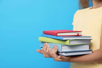 Little girl holding books on blue background, closeup. Reading concept