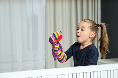 Photo of Cute little girl performing puppet show at home