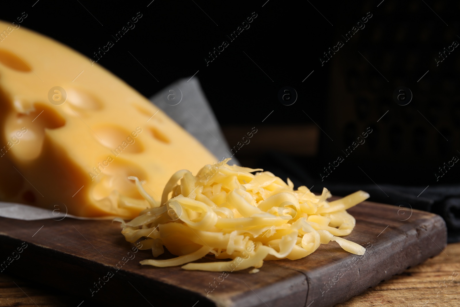 Photo of Tasty grated cheese on wooden table, closeup