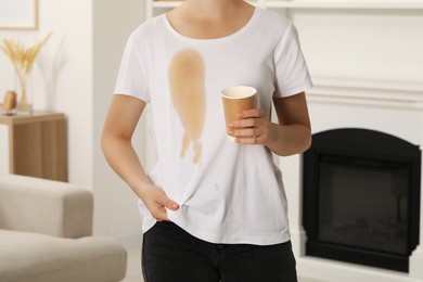 Woman showing stain from coffee on her shirt indoors, closeup