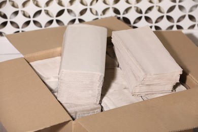 Photo of Cardboard box with paper napkins near white wall, closeup