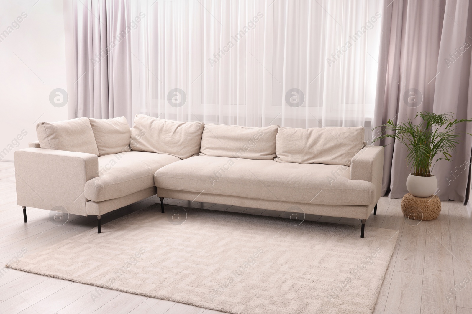 Photo of Comfortable sofa and window with beautiful curtains in room. Interior design