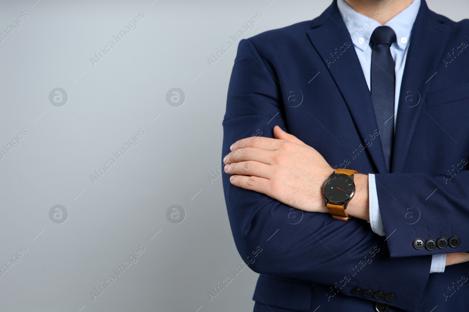 Photo of Closeup view of businessman wearing wristwatch against grey background, space for text. Time management