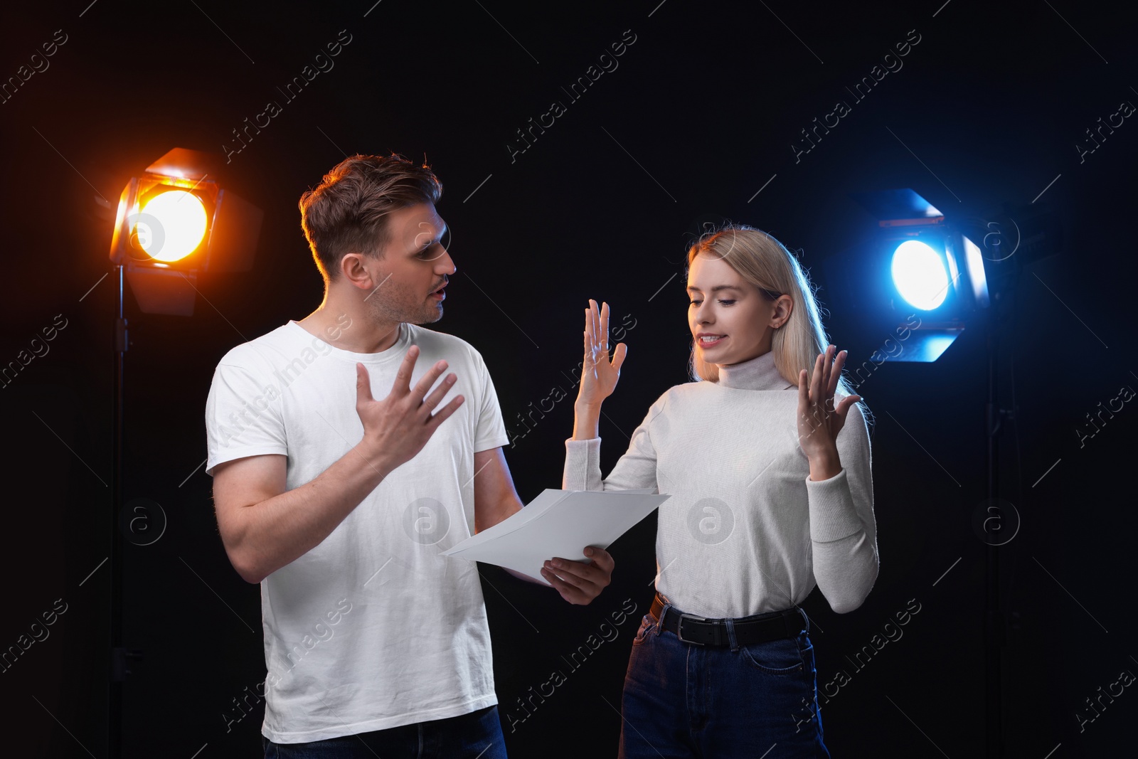 Photo of Casting call. Emotional woman and man with script performing on black background