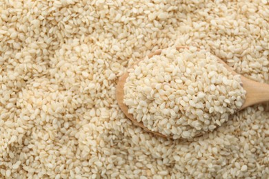 Photo of Wooden spoon on pile of white sesame seeds, top view. Space for text