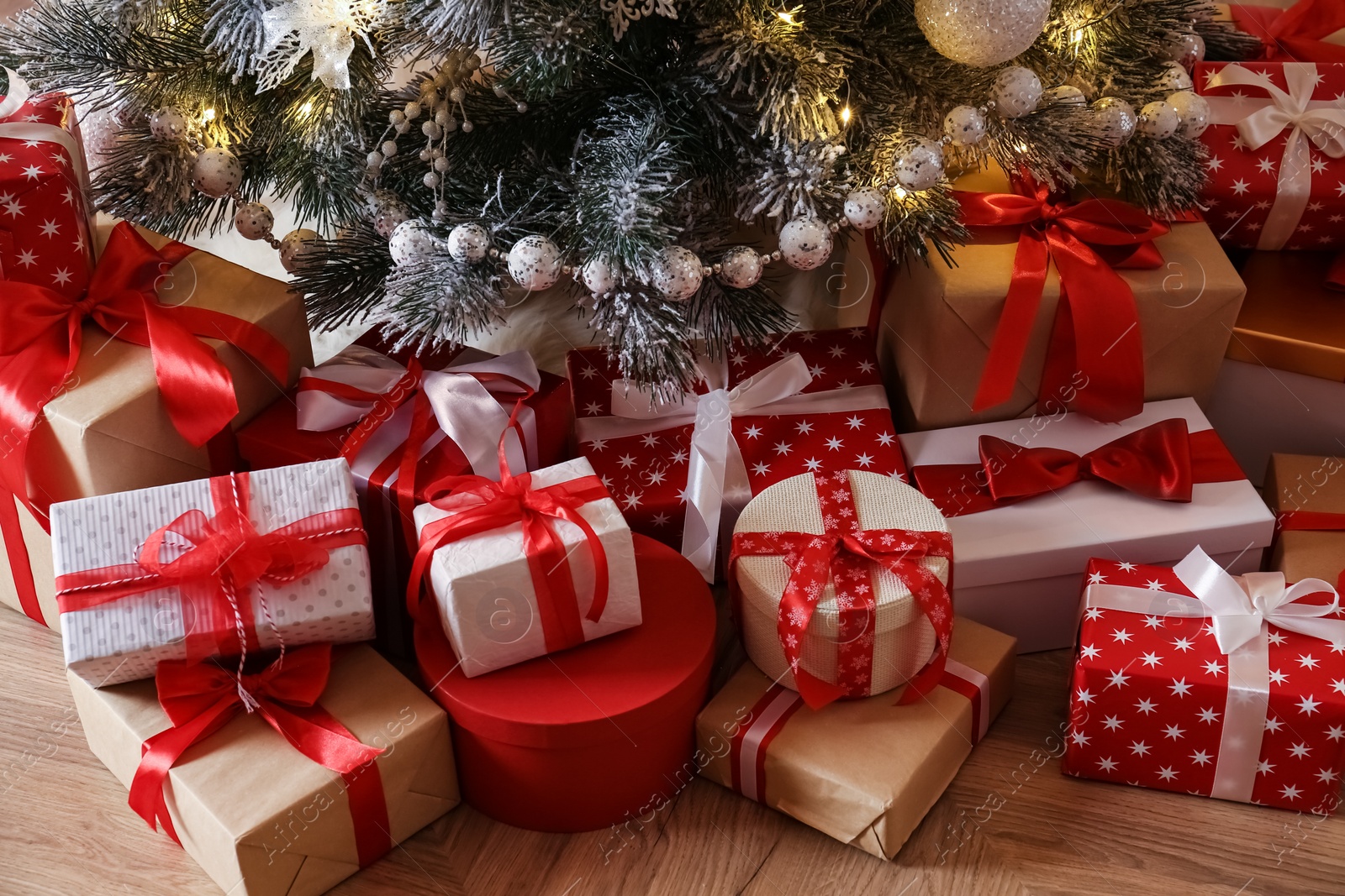 Photo of Pile of gift boxes near beautiful Christmas tree indoors