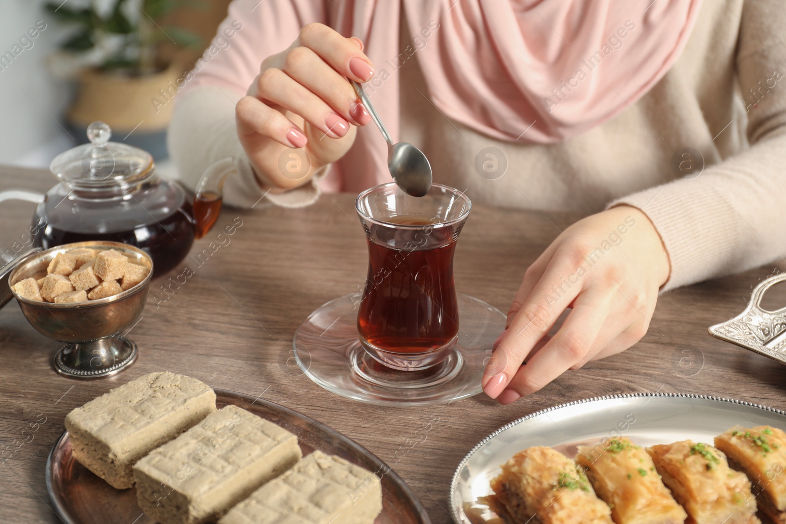 Photo of Woman with cup of delicious Turkish tea at wooden table, closeup