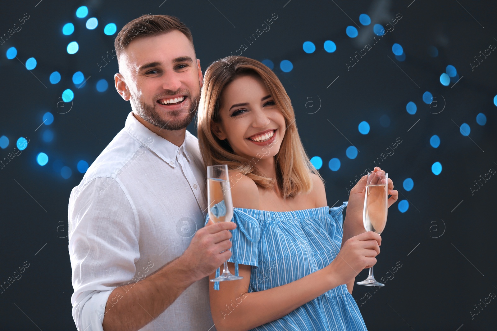 Photo of Portrait of happy couple with champagne in glasses on blurred background