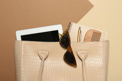 Photo of Stylish women's bag with tablet and stuff on color background, closeup