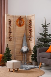 Beautiful Christmas themed photo zone with trees, dwarf and armchair in room