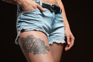 Photo of Woman with tattoos on body against black background, closeup