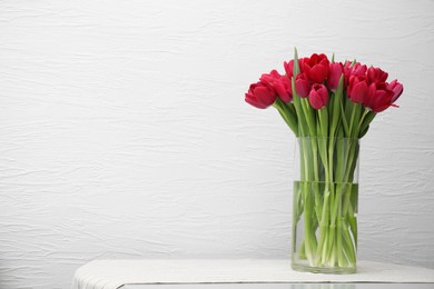 Photo of Bouquet of beautiful tulips in glass vase on table indoors. Space for text