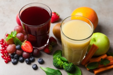 Glasses of delicious juices and fresh ingredients on grey table, closeup