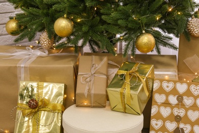 Photo of Pile of gift boxes near Christmas tree with fairy lights
