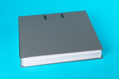 Grey hardcover office folder on light blue background