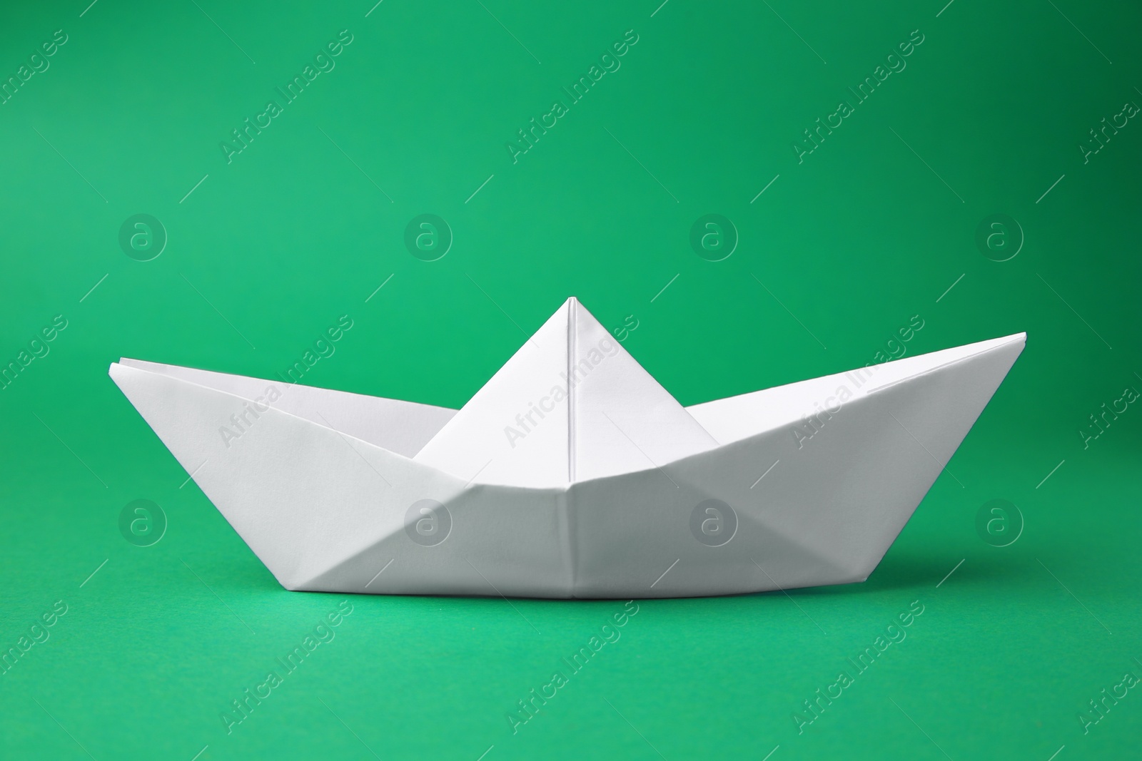 Photo of Origami art. Paper boat on green background