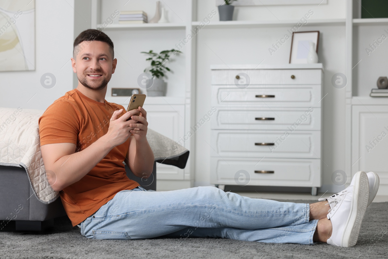 Photo of Handsome man sending message via smartphone at home. Space for text