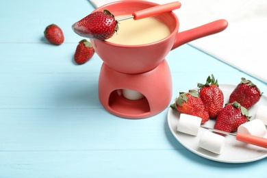 Chocolate fondue with strawberries and marshmallow on wooden table. Space for text