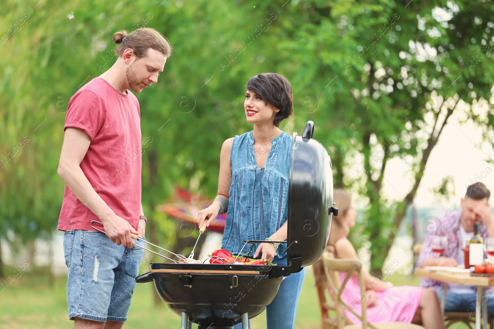 Photo of Young people having barbecue with modern grill outdoors