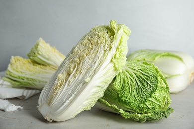 Photo of Whole and cut fresh Chinese cabbages on light grey table, closeup