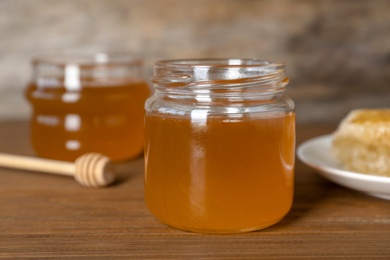 Photo of Glass jar with sweet honey on table, closeup