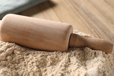 Pile of flour and rolling pin on wooden table, closeup