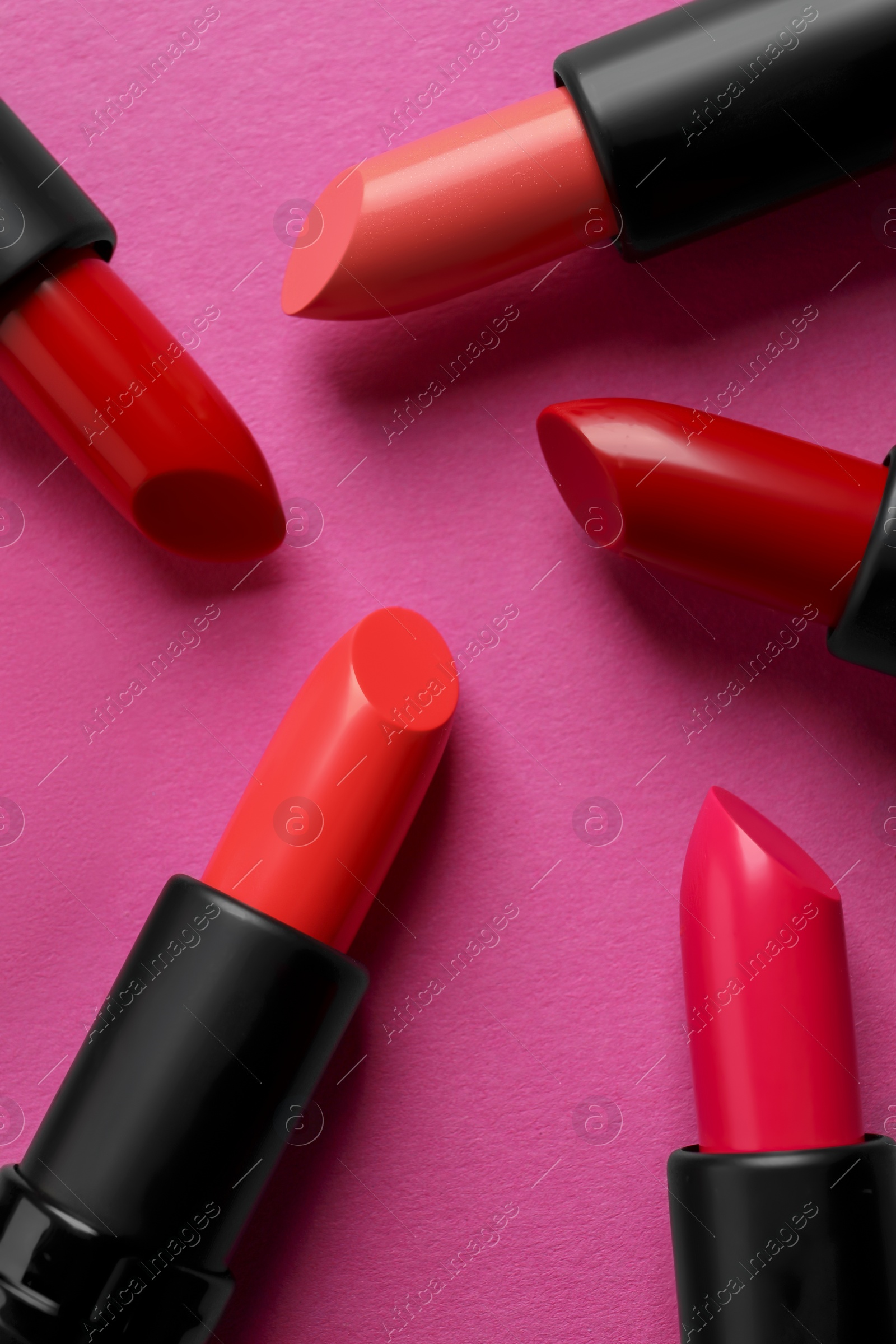 Photo of Beautiful lipsticks on pink background, flat lay