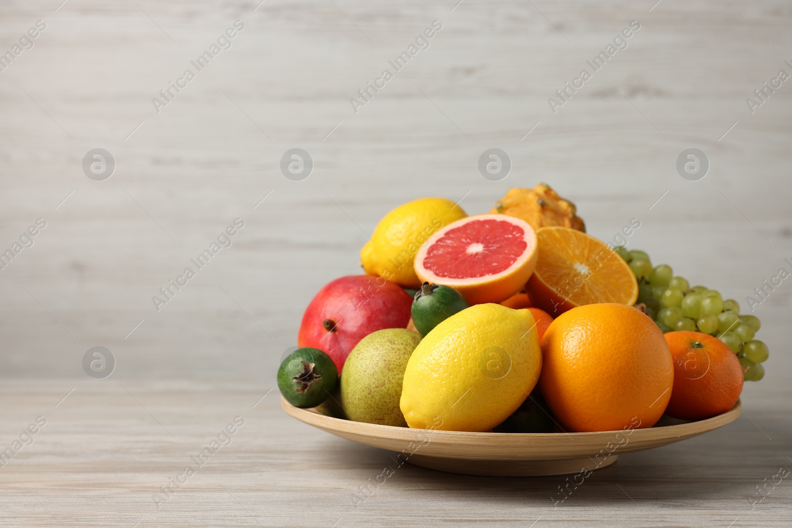 Photo of Different ripe fruits on light wooden table, space for text