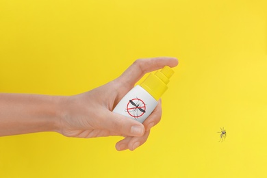 Woman spraying insect repellent on mosquito against yellow background, closeup