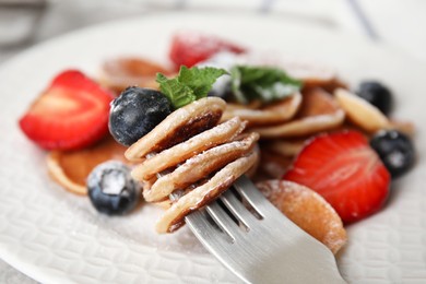 Photo of Fork with cereal pancakes, blueberry and mint on blurred background, closeup