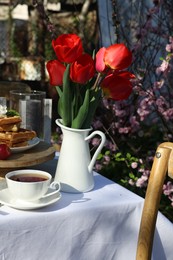 Beautiful bouquet of tulips and freshly baked waffles on table served for tea drinking in garden