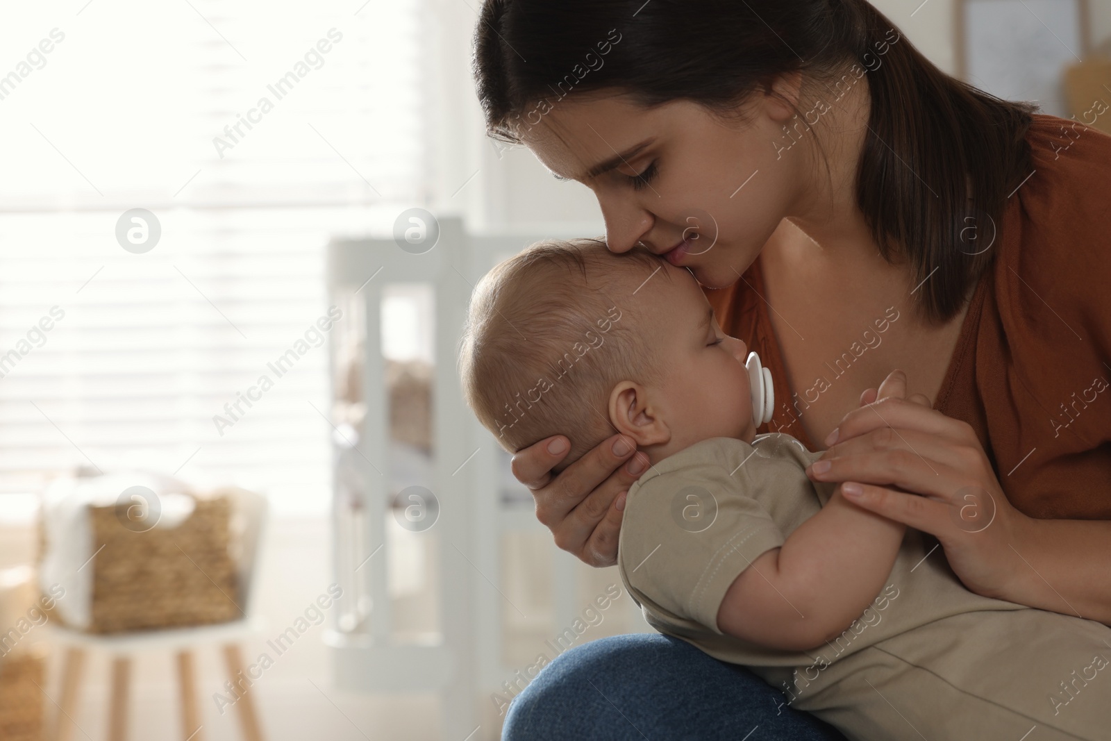 Photo of Happy young mother with her sleeping baby at home. Space for text