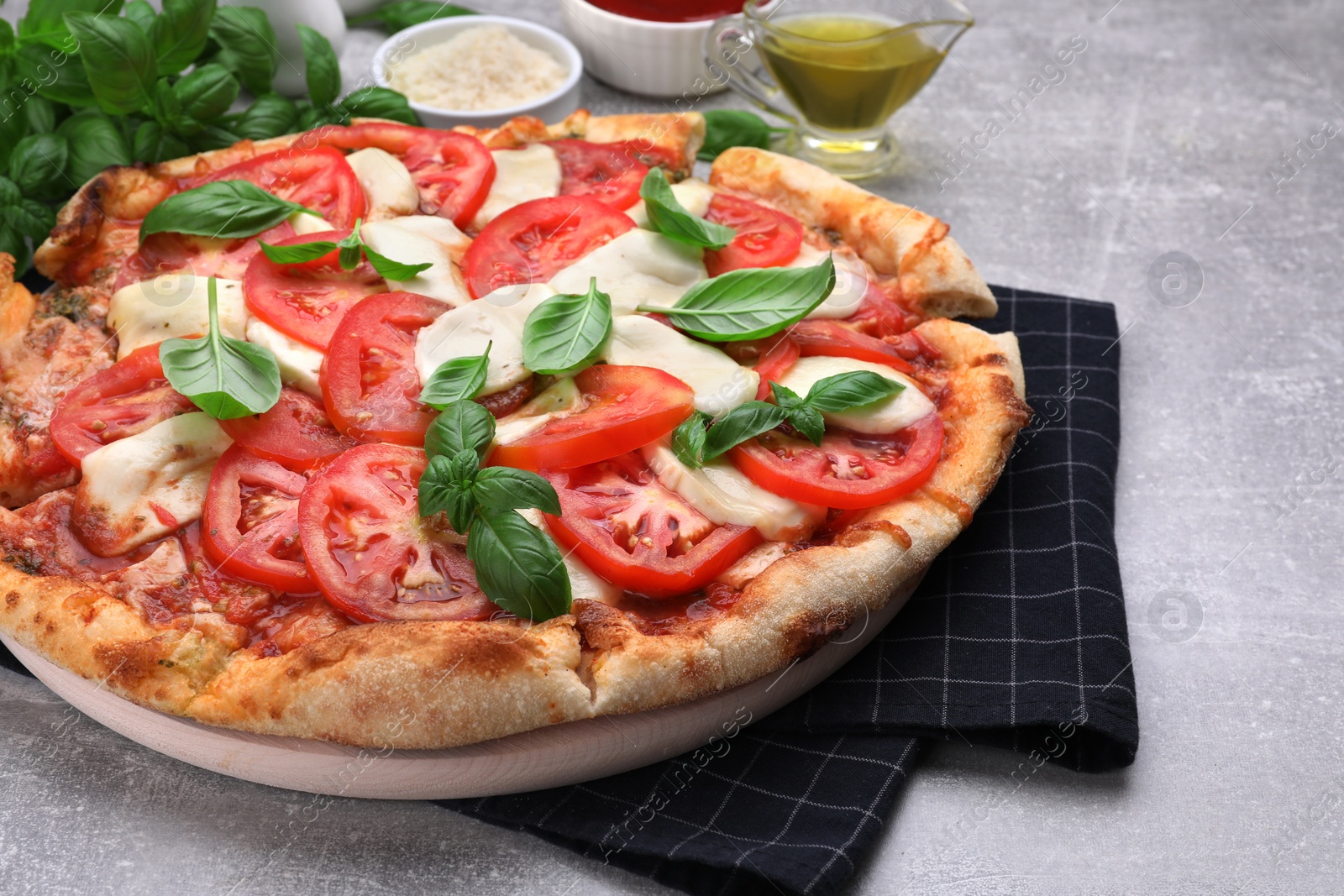 Photo of Delicious Caprese pizza with tomatoes, mozzarella and basil served on light grey table, closeup