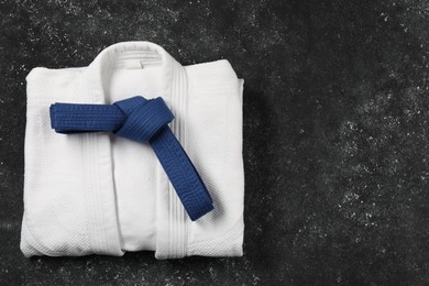 Photo of Blue karate belt and white kimono on gray background, top view. Space for text