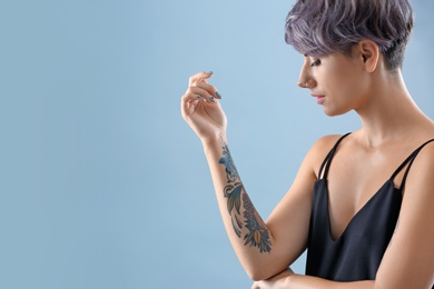 Young woman with tattoo on color background. Space for text