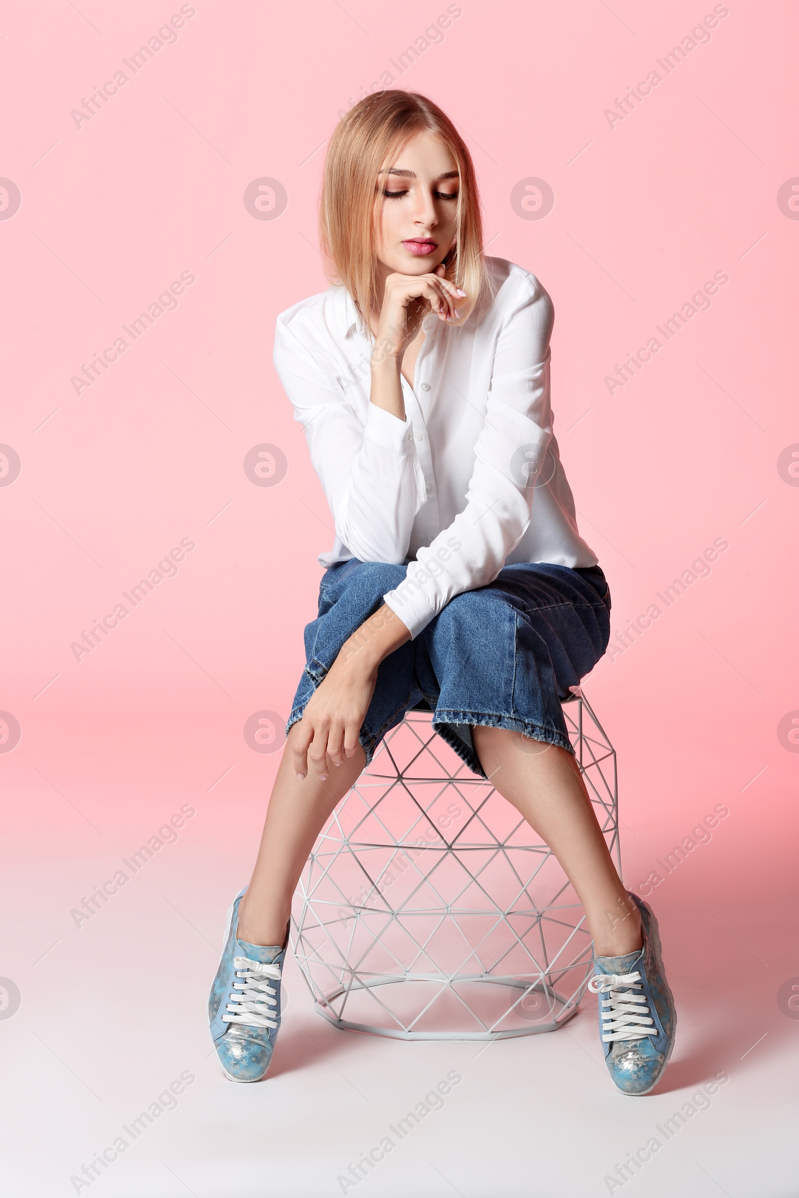 Photo of Fashionable young woman in stylish shoes on stool against color background