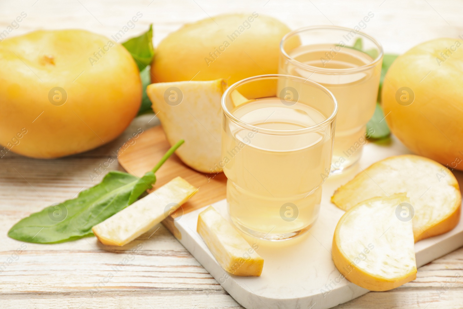 Photo of Glasses of freshly made turnip juice on white wooden table