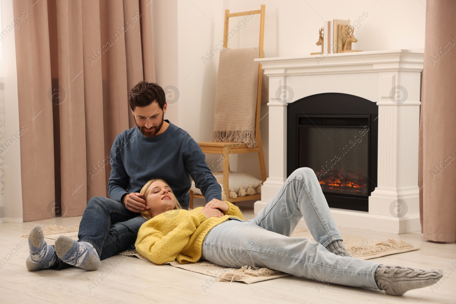 Photo of Lovely couple spending time together near fireplace indoors