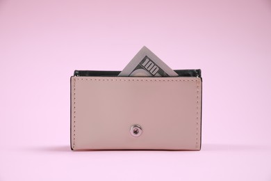 Stylish leather purse with dollar banknote on pink background