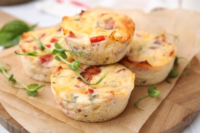 Photo of Delicious egg muffins with cheese and bacon on wooden board, closeup